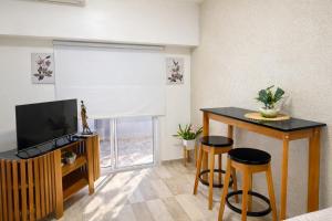 a living room with a television and a table and stools at Departamento moderno, equipado full en vicente López ,ubicacion inmejorable a 100 metros del tren in Florida