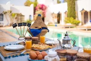 a table with plates of food and a basket of orange juice at ecrin mogador in Aït Sidi Saïd