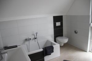 a bathroom with a white tub and a toilet at Ferienhaus "Dorf-Glück" in Brilon +16 photos