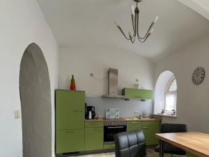 eine Küche mit grünen Schränken und einem Tisch mit Stühlen in der Unterkunft Grüne Villa in Kromlau