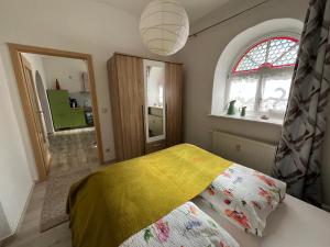 ein Schlafzimmer mit einem Bett mit einer gelben Decke in der Unterkunft Grüne Villa in Kromlau