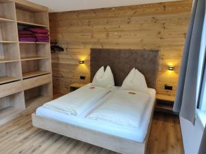 a bedroom with a bed with white sheets and shelves at Appartement Fritzenwallner in Wagrain +77 photos