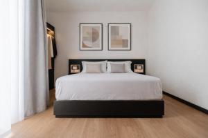 a bedroom with a white bed with two pictures on the wall at Aspio Hotel in Osimo