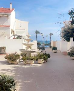 a fountain in the middle of a courtyard with palm trees at Seafront Chalet Muchavista direct beach access in El Campello