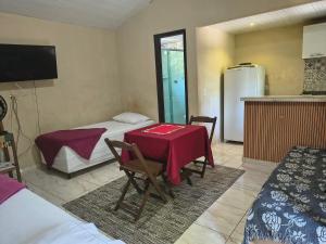 a room with a table and a kitchen with a refrigerator at Pousada do Trevo in Paraty