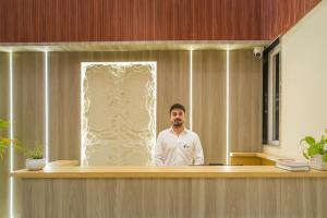 a man standing behind a counter in an office at Tripli Hotels Solune in Rishīkesh