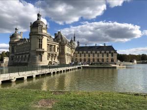 a large building with a bridge over a body of water at La Petite Maison in Arsy