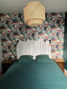 a bedroom with a green bed with a floral wallpaper at La Petite Maison in Arsy