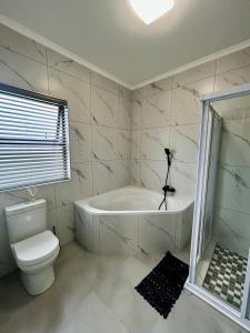 a bathroom with a white tub and a toilet at EHH Accommodation Hentiesbay in Hentiesbaai +18 photos