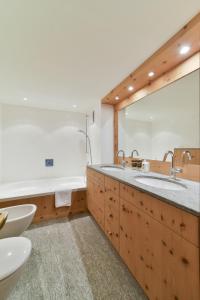 a bathroom with two sinks and a large mirror at Chesa Pino - Madulain in Madulain +32 photos