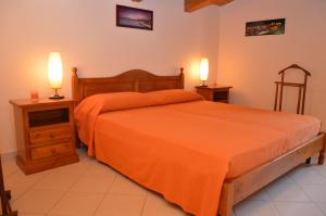 1 dormitorio con 1 cama de color naranja y 2 lámparas en Villa Giulia - Sicilian Luxury Garden, en Punta Secca