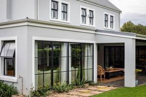 a white house with large sliding glass doors at Dornoch House, Gowrie Village in Nottingham Road