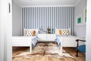 two beds in a room with a striped wall at Dornoch House, Gowrie Village in Nottingham Road