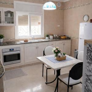 a kitchen with a table and chairs and a refrigerator at La Perle de Hergla Maison d Hotes in Harqalah