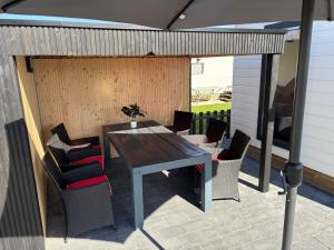 a patio with a wooden table and chairs at Chalet Lutafaro near beach Petten in Petten +9 photos