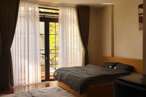 a bedroom with a bed and a large window at Prova Home in Da Lat