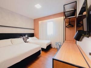 a hotel room with two beds and a tv at ibis Curitiba Shopping in Curitiba +116 photos