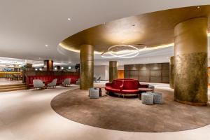 a lobby with a red couch and tables and chairs at Hilton Birmingham Metropole Hotel in Bickenhill
