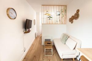 a living room with a white chair and a tv at La casa del Platana in Domagné
