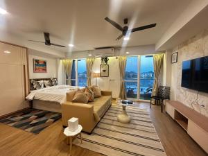 a bedroom with a bed and a couch and a tv at Atelier Sol- ultra luxe aparthotel near airport in Pune