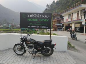 a motorcycle parked next to a home stay sign at Hotel Dharohar in Gopeshwar