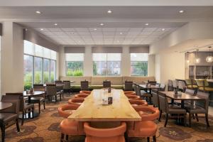 a restaurant with wooden tables and chairs and windows at Hilton Garden Inn Wooster in Wooster