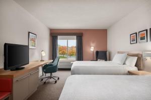 a hotel room with two beds and a desk with a television at Hilton Garden Inn Wooster in Wooster
