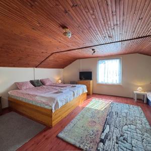 a bedroom with a large bed and a wooden ceiling at Viktória Apartman DunaWeekend in Makád