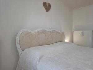 a white bed with a heart on the wall at La casa nel borgo in Cavaso del Tomba
