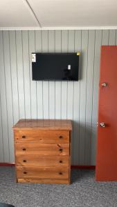 a flat screen tv on a wall with a wooden dresser at Hostal Santa Sabina in Concepción