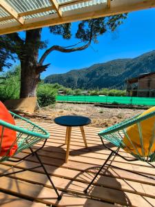 two chairs and a table on a deck at Cabaña El Refugio in Lago Puelo