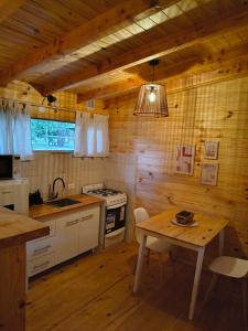 a kitchen with a table and a sink and a stove at Cabaña El Refugio in Lago Puelo