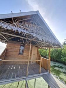 a wooden building with a roof on the beach at Kombrof Homestay & Dive Center in Waisai +26 photos