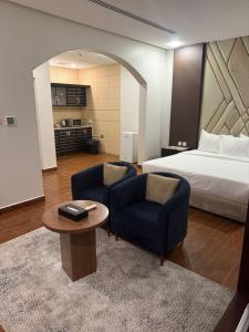 a bedroom with a bed and two chairs and a table at ريف الشرقية للشقق الفندقية in Dammam