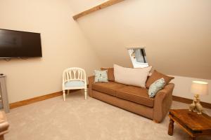 a living room with a couch and a tv on the wall at The Plough Inn in Stalisfield