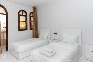 two beds in a room with white walls at Erraha Hostel Dakhla in Dakhla