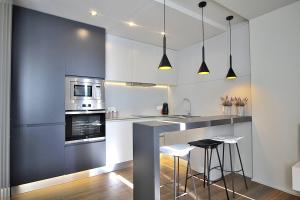 a kitchen with white cabinets and a counter with stools at RestOnDouro Oporto Flat in Valbom