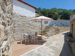 a table with an umbrella next to a stone wall at RestOnDouro Oporto Flat in Valbom +19 photos