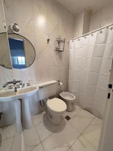 a white bathroom with a toilet and a sink at Hotel Florida in Concordia