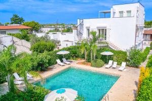 a swimming pool with chairs and umbrellas in front of a house at Residence Le Piscine in Nardò