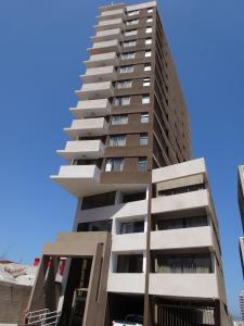 a tall apartment building in front of a blue sky at Tempora Apart Hotel in Antofagasta