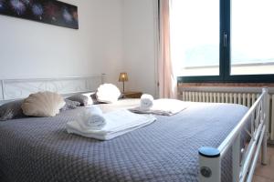 a bedroom with two towels on a bed with a window at Casa Segantini - Panorama Pool Apartment in Riva del Garda +36 photos