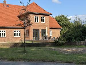a house with an orange roof and a tree in the yard at Hostel Farm Ostedt in Wrestedt