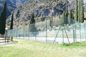 a tennis court with a fence in front of a mountain at Casa Segantini - Panorama Pool Apartment in Riva del Garda