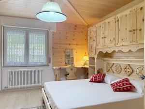 a bedroom with a large white bed with red pillows at Lagorai Wood Apartment in Telve