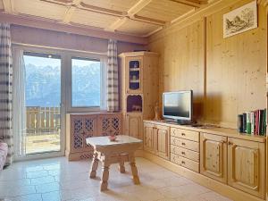 a living room with a tv and a table in it at Lagorai Wood Apartment in Telve