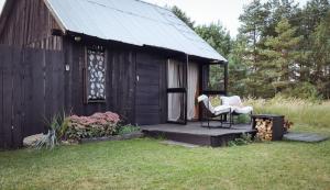 a small cabin with two chairs on the porch at Drewutnia nad Hańczą in Sernetki