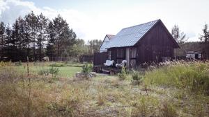 an old barn with a chair in a field at Drewutnia nad Hańczą in Sernetki