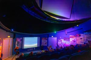 a stage with a crowd of people and a screen at LE HAMEAU DES ETOILES in Fleurance
