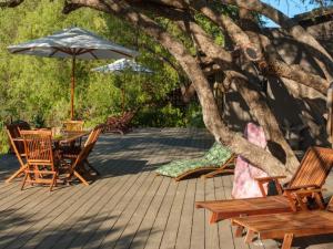 a patio with a table and chairs and an umbrella at Kamala Karoo Sanctuary in Barrydale